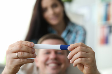 Happy man holding pregnancy test