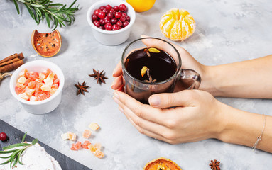 Female hands hold a cup of mulled wine on concrete background.
