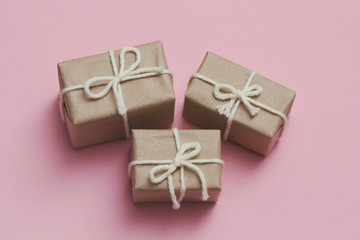Set of parcels wrapping in brown craft paper and tie hemp string. Package. Delivery service. Online shopping. Your purchase. Gift box on a table. Pink solid background.