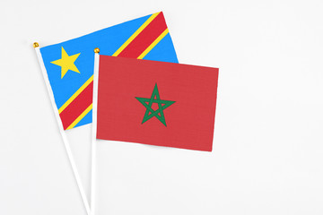 Morocco and Congo stick flags on white background. High quality fabric, miniature national flag. Peaceful global concept.White floor for copy space.