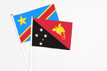 Papua New Guinea and Congo stick flags on white background. High quality fabric, miniature national flag. Peaceful global concept.White floor for copy space.