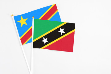 Saint Kitts And Nevis and Congo stick flags on white background. High quality fabric, miniature national flag. Peaceful global concept.White floor for copy space.