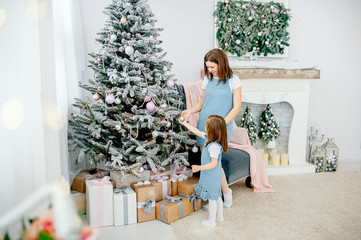 Beautiful girl with mom decorates the Christmas tree at home. Happy family. Merry Christmas and Happy New Year.