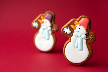 gingerbread cookie of cute snowman on red background. Traditional Christmas food. Christmas and New Year holiday concept.