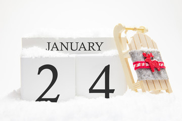 Wooden calendar for January, 24 th day of the winter month. The symbols of winter are snow and sleigh. Concept of holidays, vacation and winter fun.