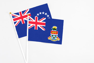 Fototapeta premium Cayman Islands and Cook Islands stick flags on white background. High quality fabric, miniature national flag. Peaceful global concept.White floor for copy space.