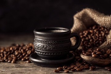 Coffee cup with coffee beans on wood background.