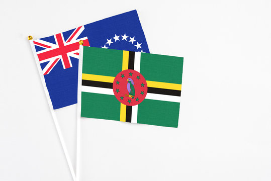 Dominica and Cook Islands stick flags on white background. High quality fabric, miniature national flag. Peaceful global concept.White floor for copy space.