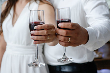 hands with wedding rings holding wine glasses