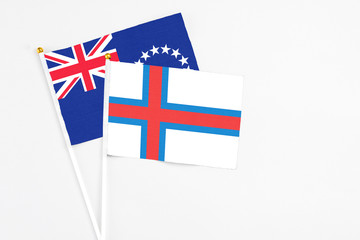 Faroe Islands and Cook Islands stick flags on white background. High quality fabric, miniature national flag. Peaceful global concept.White floor for copy space.