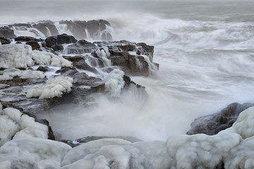 Powerful sea waves breaking on the rocky coast. Winter seascape.