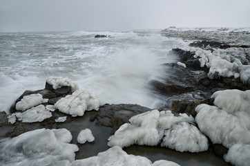 Powerful sea waves breaking on the rocky coast. Winter seascape.