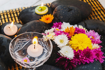 Fototapeta na wymiar Wet black stones with chrysanthemum buds, decor for spa, relaxation and massage