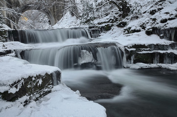 Mountain winter scene of a beautiful waterfall in the forest