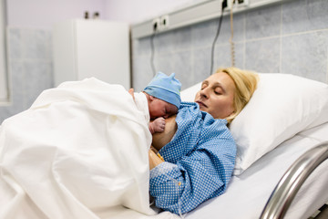Obraz na płótnie Canvas Mother and newborn baby laying and resting in hospital bed. After birth concept.