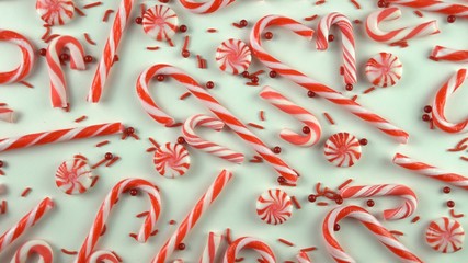 Close up of Christmas Eve season red color mood table with candy canes and peppermint spinning over white background. Holiday scene with pearls sprinkles.