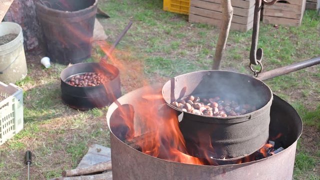 Close up of a large pan with roasting chestnuts above the fire. Autumn traditional festival of chestnuts in Italy.
