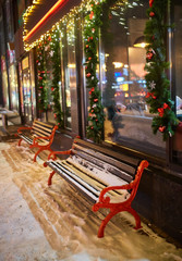 Fototapeta na wymiar View of bench and shining lantern through snowing.