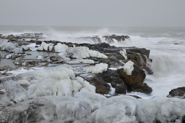 Powerful sea waves breaking on the rocky coast. Winter seascape.