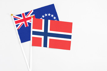 Norway and Cook Islands stick flags on white background. High quality fabric, miniature national flag. Peaceful global concept.White floor for copy space.
