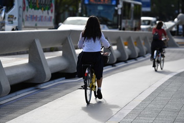 A young female student is driving over a bridge of the river Motoyasu in Hiroshima white her bicycle.