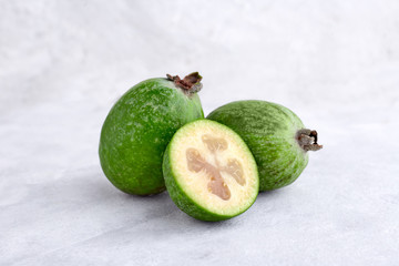 Green feijoa fruits on gray concrete background table. Tropical fruit feijoa. Set of ripe feijoa fruits.