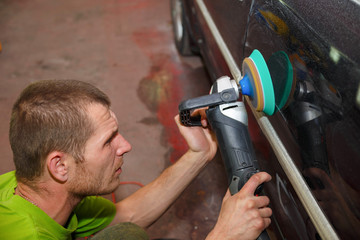 The master polishes the car with a grinder with paste.
