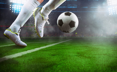 Football scene at night match with close up of a soccer player running to kick the ball at the...