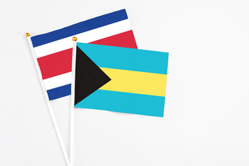 Bahamas and Costa Rica stick flags on white background. High quality fabric, miniature national flag. Peaceful global concept.White floor for copy space.