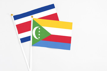 Comoros and Costa Rica stick flags on white background. High quality fabric, miniature national flag. Peaceful global concept.White floor for copy space.