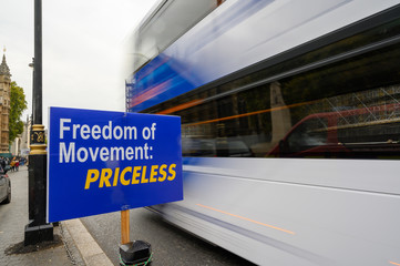 White London bus with motion blur as it passes anti-Brexit Freedom of Movement sign