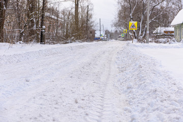 Winter, snowy road. Traces of a car in the snow. Snowdrifts of snow.
