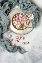 Fototapeta na wymiar Metal sieve with dried flowers of rose on gray background