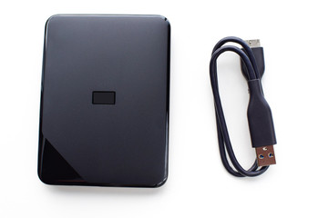 External hard drive with connecting cable on a white  background. Gadgets and computer accessories.	