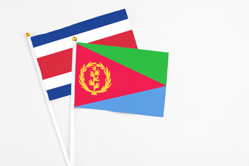 Eritrea and Costa Rica stick flags on white background. High quality fabric, miniature national flag. Peaceful global concept.White floor for copy space.