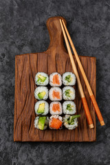 Sushi set on cutting wooden board. Avocado, salmon and cucumber