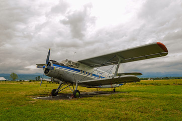 old airplane stands in a field, gray cloudy sky, selective focus