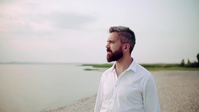 Waist up portrait of mature man on a holiday standing by the lake.