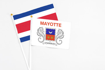 Mayotte and Costa Rica stick flags on white background. High quality fabric, miniature national flag. Peaceful global concept.White floor for copy space.