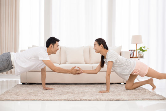 Young Chinese couple exercising in living room