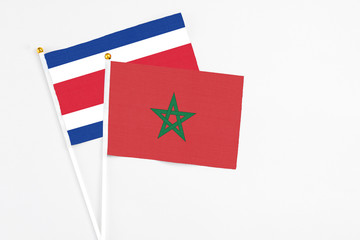Morocco and Costa Rica stick flags on white background. High quality fabric, miniature national flag. Peaceful global concept.White floor for copy space.