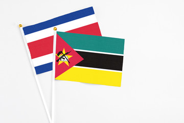 Mozambique and Costa Rica stick flags on white background. High quality fabric, miniature national flag. Peaceful global concept.White floor for copy space.
