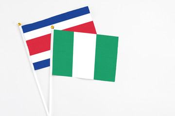 Nigeria and Costa Rica stick flags on white background. High quality fabric, miniature national flag. Peaceful global concept.White floor for copy space.
