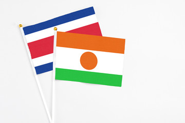 Niger and Costa Rica stick flags on white background. High quality fabric, miniature national flag. Peaceful global concept.White floor for copy space.