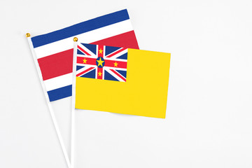 Niue and Costa Rica stick flags on white background. High quality fabric, miniature national flag. Peaceful global concept.White floor for copy space.