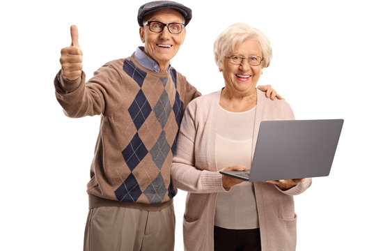 Senior man showing thumb up and a senior woman holding a laptop