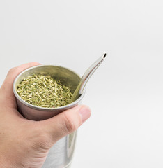Hand holding a cup of Terere drink. Cold beverage typical from the midwest of brazil. Infusion of...