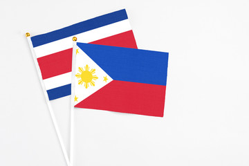 Philippines and Costa Rica stick flags on white background. High quality fabric, miniature national flag. Peaceful global concept.White floor for copy space.