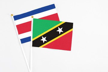 Saint Kitts And Nevis and Costa Rica stick flags on white background. High quality fabric, miniature national flag. Peaceful global concept.White floor for copy space.