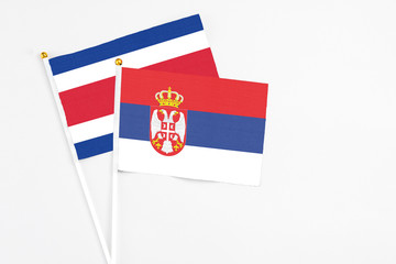 Serbia and Costa Rica stick flags on white background. High quality fabric, miniature national flag. Peaceful global concept.White floor for copy space.